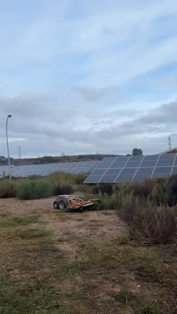Robot de desbroce trabajando bajo paneles solares
